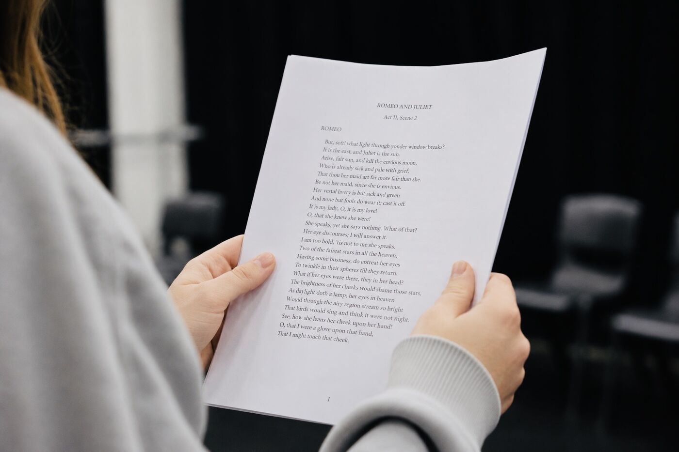 A student's hands holding a marked-up script